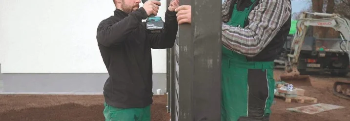 Zwei Personen montieren einen Zaun.