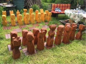 Ein riesiges Schachspiel aus Holz auf einem Rasen.
