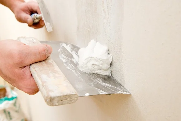 Person verputzt Wand mit Spachtel