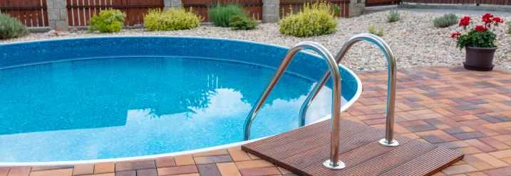 Runder Pool mit Leiter auf einer gepflasterten Terrasse