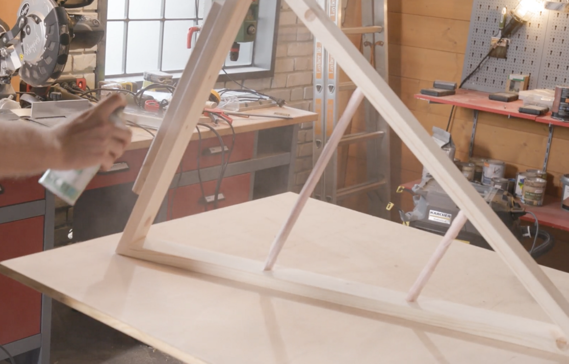 Person sprüht Holzrahmen weiß