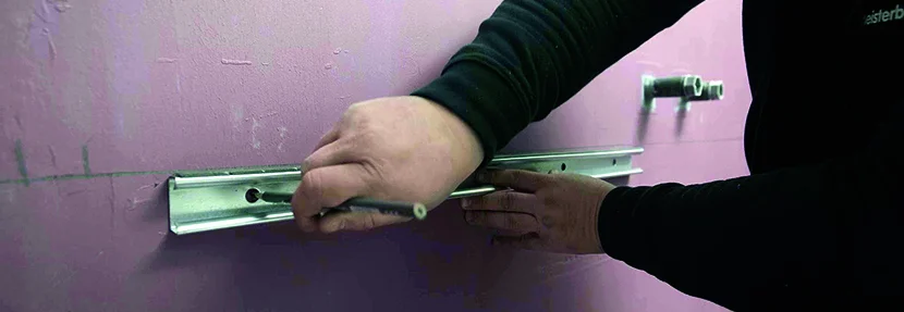 Person bringt Metallschiene an Wand an