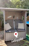 Ein selbstgebauter Strandkorb aus Holz mit Kissen und dem Schriftzug 'Lieblingsplatz'.