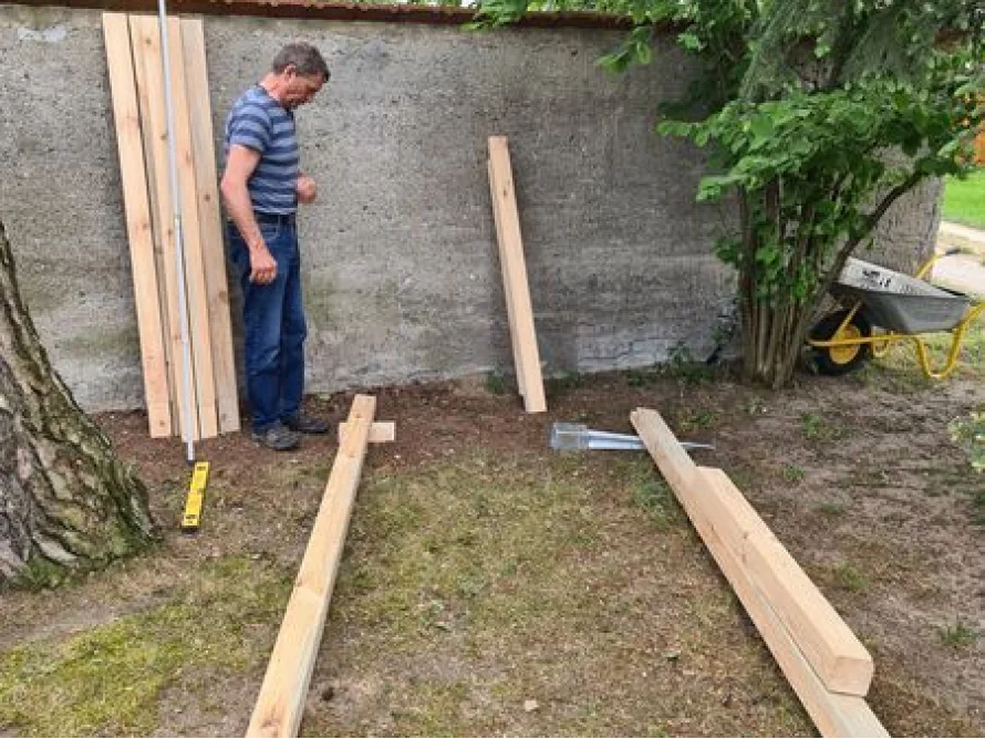 Person baut ein Gartenhaus aus Holz