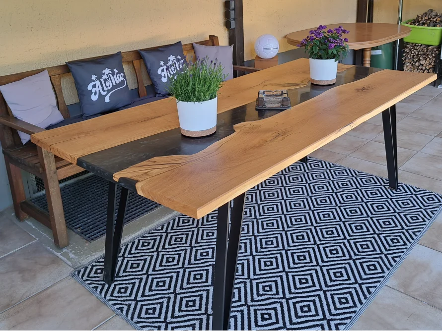 Ein Esstisch aus hellem Holz mit einer schwarzen Einlage