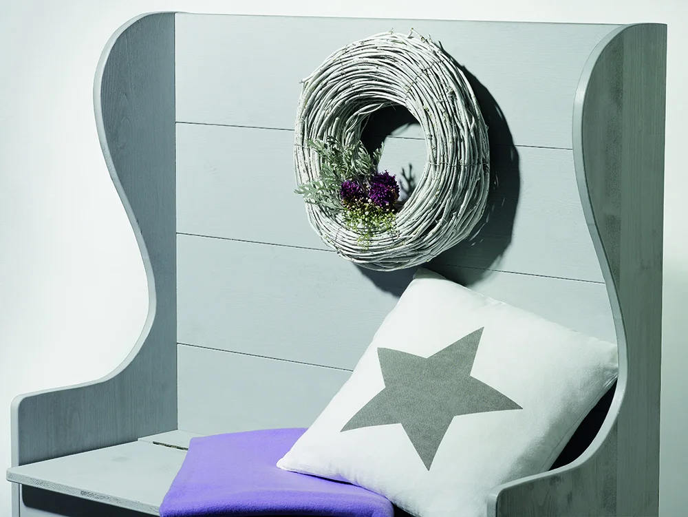 Graue Holzbank mit Kissen und Kranz