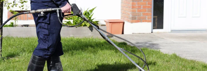 Person reinigt eine Auffahrt mit einem Hochdruckreiniger.