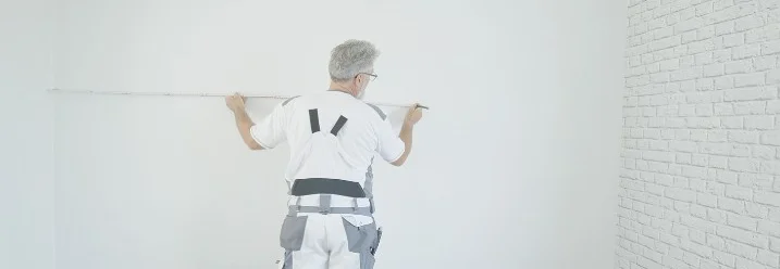 Person misst Wand mit Zollstock aus