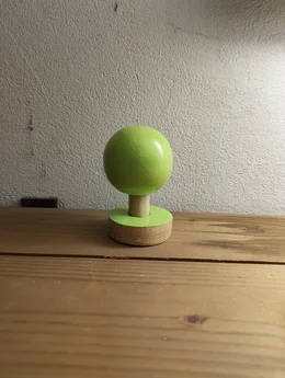 Grüne, stilisierte Baumfigur aus Holz auf einem Holztisch.