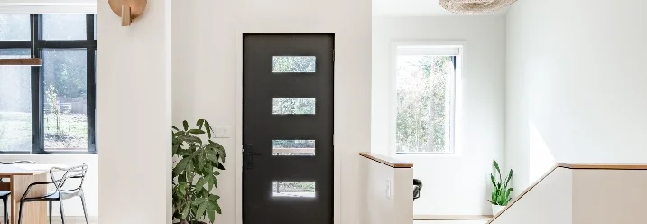 Heller Flur mit schwarzer Tür und Treppe