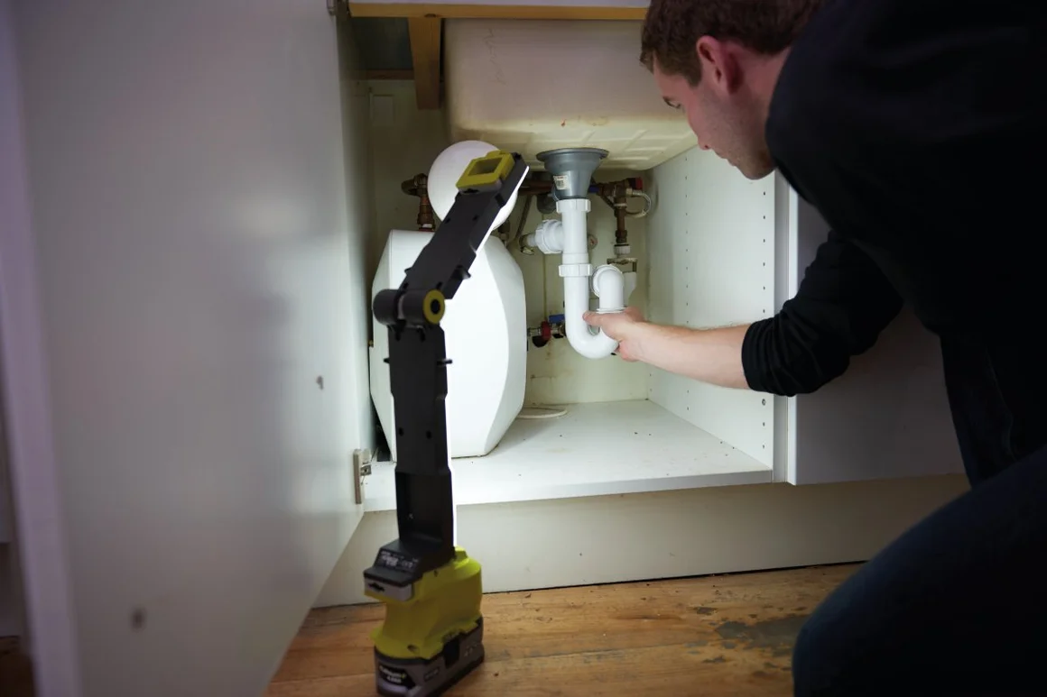 Person repariert Siphon mit Arbeitsleuchte