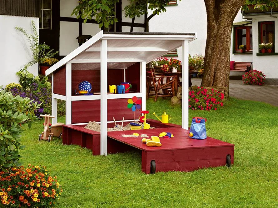 Roter und weißer Sandkasten mit Dach