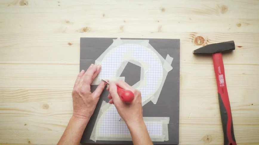 Hände schneiden mit einem Cutter eine Schablone zu