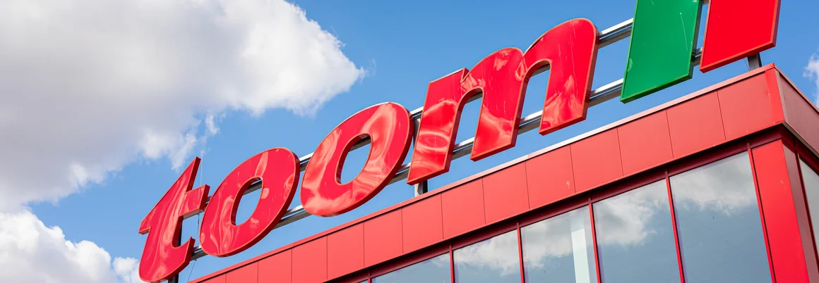 Rotes Gebäude mit großem toom Logo und blauem Himmel im Hintergrund