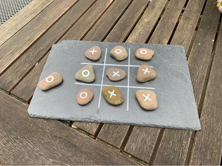 Tic-Tac-Toe Spiel mit Steinen auf Schieferplatte