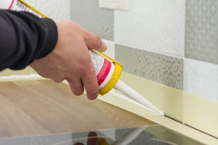 Hand trägt Dichtmittel mit Kartusche auf