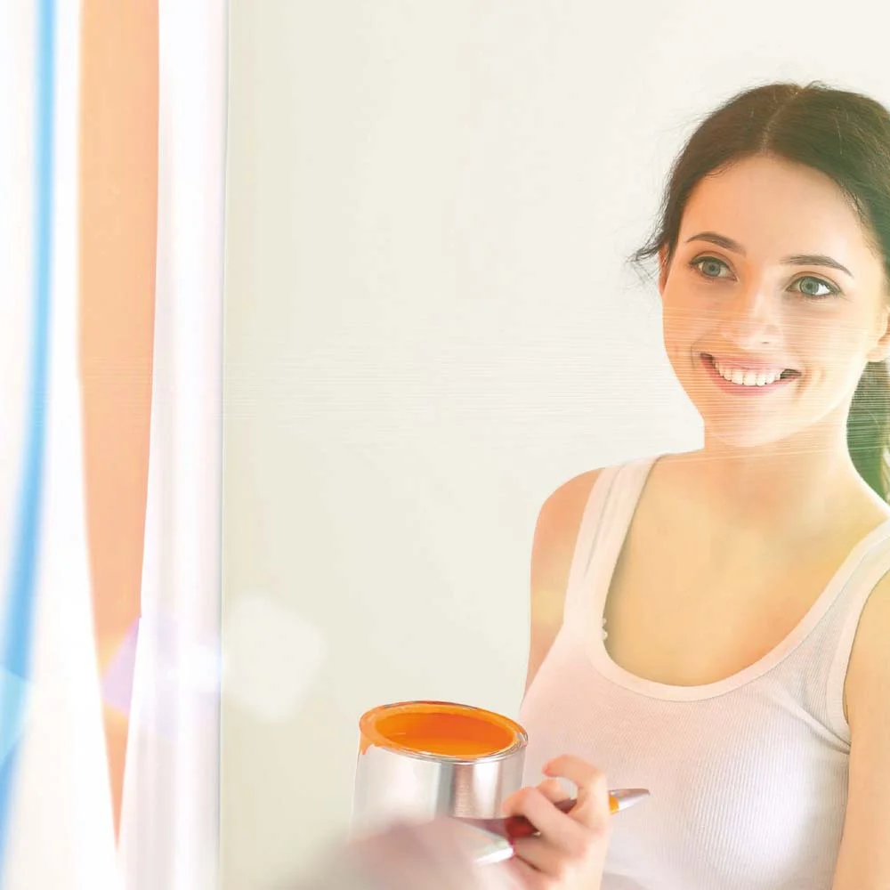 Person lächelt und hält Farbe und Pinsel