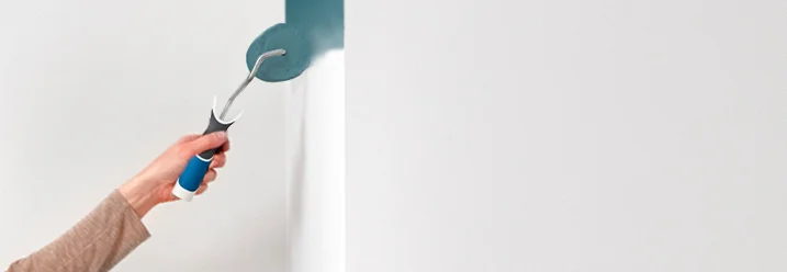 Hand streicht Wand mit Farbrolle