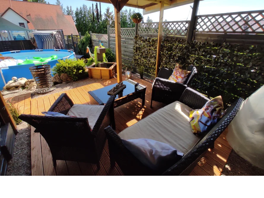 Gartenmöbel auf einer Terrasse mit Pool im Hintergrund