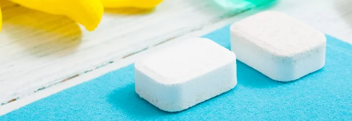 Zwei weiße Reinigungstabs auf blauem Tuch