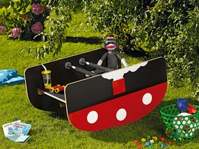 Rotes und schwarzes Spielzeugboot auf Gras