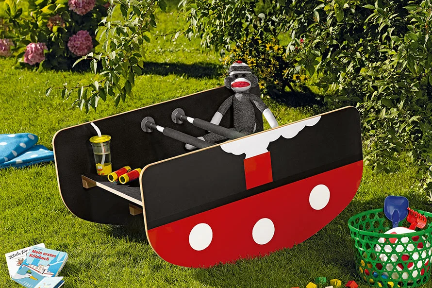 Rotes und schwarzes Spielzeugboot auf Gras