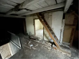 Verlassener Dachboden mit Holztreppe und Baumaterialien
