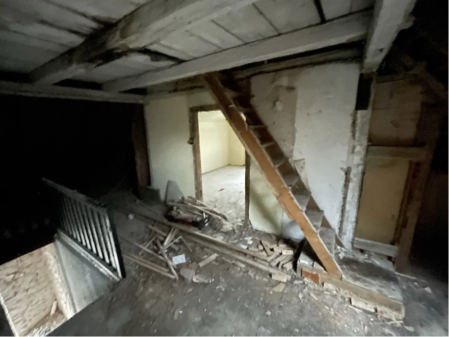 Verlassener Dachboden mit Holztreppe und Baumaterialien