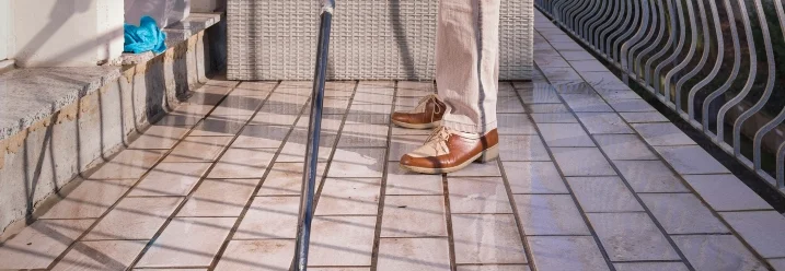 Person fegt nassen Fliesenboden mit Besen