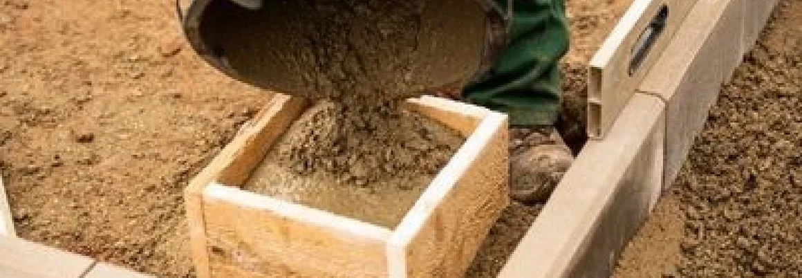 Person gießt Beton in eine Holzschalung