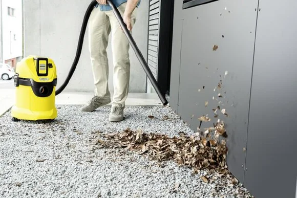 Person saugt Laub mit einem Industriesauger.