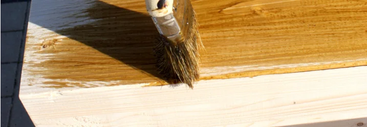 Pinsel trägt Lasur auf Holz auf