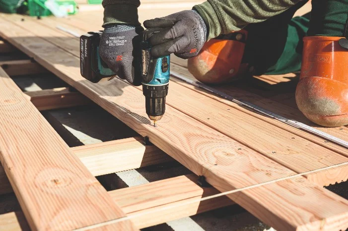 Person verschraubt Holzbretter mit Akkuschrauber