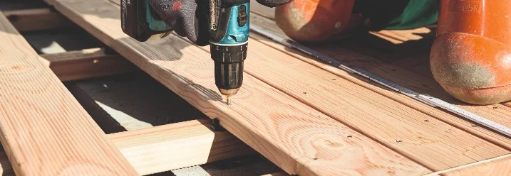 Person verschraubt Holzbretter mit Akkuschrauber