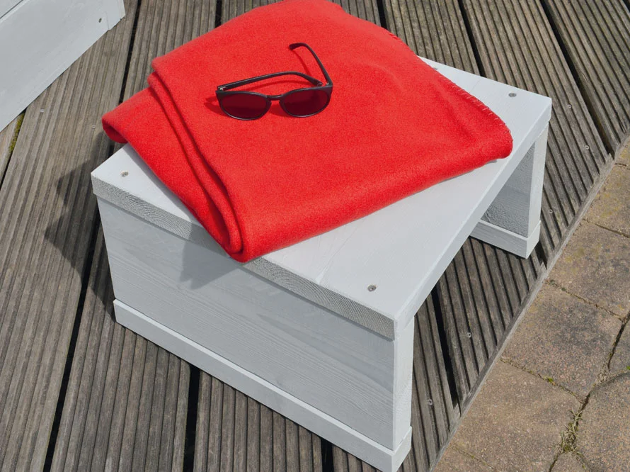 Weiße Holzbank mit rotem Tuch und Sonnenbrille