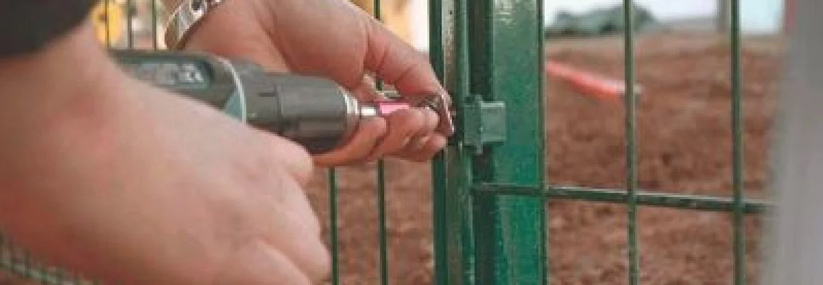 Person befestigt Zaun mit Akkuschrauber