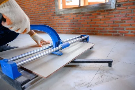 Person schneidet Fliese mit Fliesenschneider