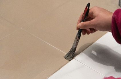 Frau streicht Fliesen mit Pinsel