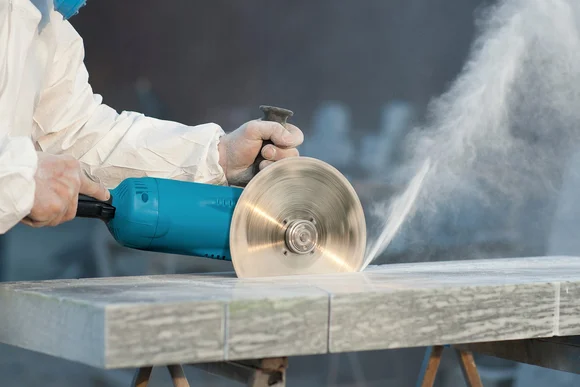Person schneidet Stein mit Trennschleifer