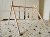 Ein Baby-Spielbogen aus Holz mit daran befestigtem Spielzeug.