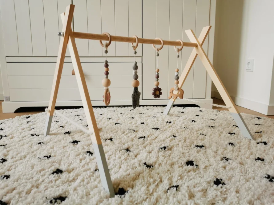 Ein Baby-Spielbogen aus Holz mit daran befestigtem Spielzeug.