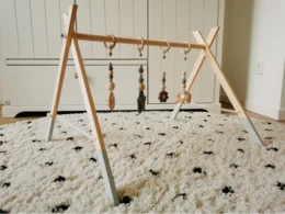 Ein Baby-Spielbogen aus Holz mit daran befestigtem Spielzeug.