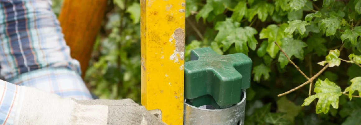 Person richtet Zaunpfosten mit Wasserwaage aus