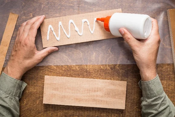 Person trägt Leim auf Holz auf