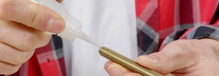 Person trägt Klebstoff auf Schraube auf