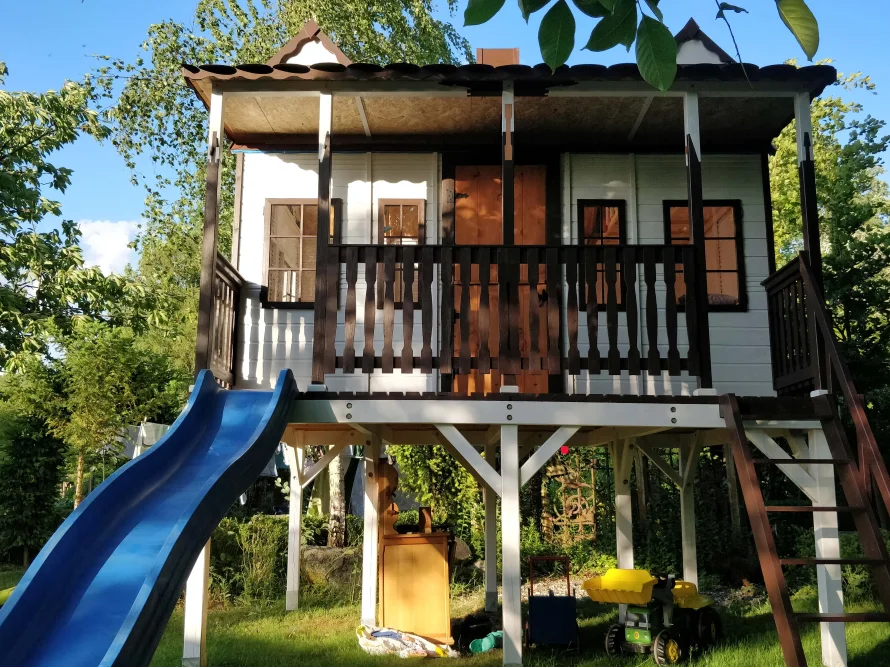 Spielhaus aus Holz mit blauer Rutsche