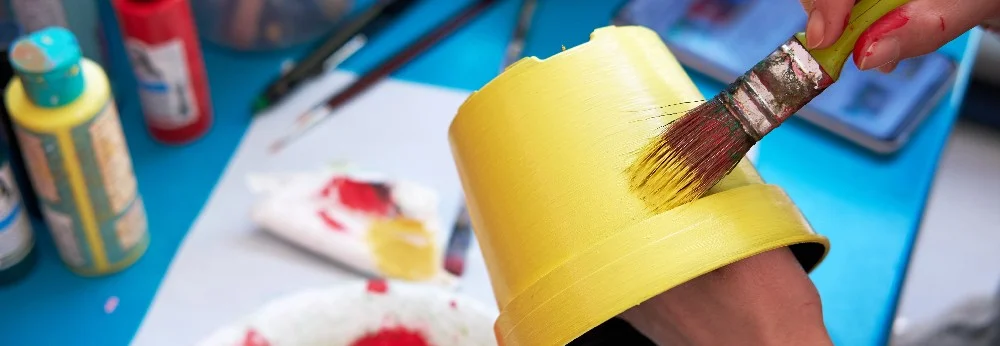 Person bemalt Topf mit Pinsel gelb.