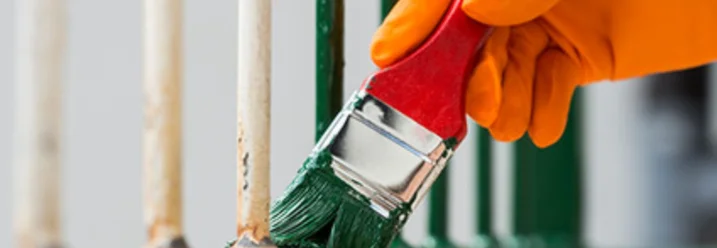 Hand mit Pinsel streicht grüne Farbe auf Metall