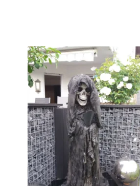 Skelettfigur mit Sense in einem Garten