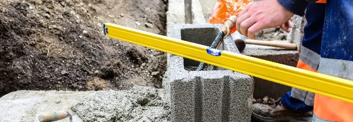 Person baut Gartenmauer mit Wasserwaage